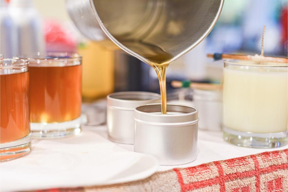 Lisa pouring molten soy wax into candle tins by hand